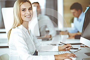 Business woman using computer at workplace in modern office. Secretary or female lawyer smiling and looks happy. Working