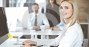 Business woman using computer at workplace in modern office. Secretary or female lawyer smiling and looks happy. Working