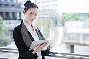 Business woman using digital tablet computer outside office. happy young beautiful girl working on social media outdoor over
