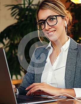 Business woman using laptop at cafe. Young beautiful girl sitting in a coffee shop and working on computer.