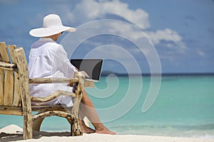 Business woman using laptop computer on the beach