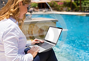 Business woman using laptop computer on vacation in resort by the pool
