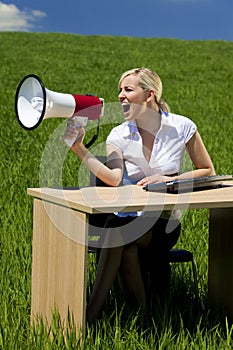 Business Woman Using Megaphone In A Green Field