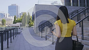 Business woman using phone while walking to office