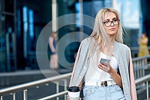 Business woman using smart phone on a background office building