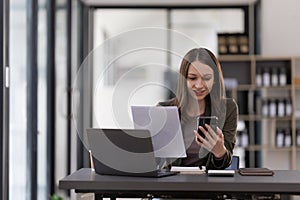 Business woman using smartphone for do math finance on wooden desk in office, tax, accounting, financial concept.