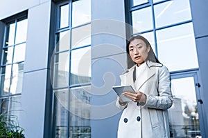 Business woman using tablet computer, office worker near office center, thoughtful and successful woman freelancer