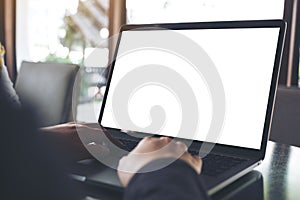 Business woman using and typing on laptop with blank white screen on table in cafe