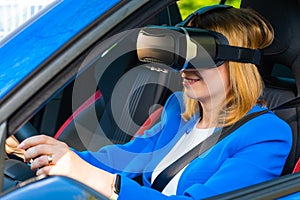 Business woman in the VR googles sitting in the car and turning the steering wheel in a car