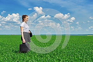 Business woman walk on green grass field outdoor. Beautiful young girl dressed in suit, spring landscape, bright sunny day