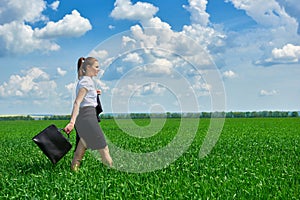 Business woman walk on green grass field outdoor. Beautiful young girl dressed in suit, spring landscape, bright sunny day