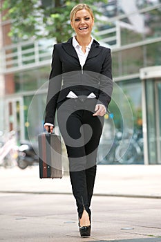 Business woman walking in the city with briefcase