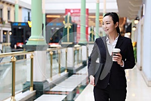 Business woman walking drinking coffee in shopping mall