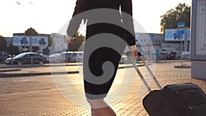 Business woman walking with her suitcase from airport hall or waiting room. Young girl in heels going from terminal and
