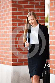 Business woman walking on stairs outdor carying business folder and hand bag