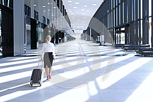 Business woman walking with wheeled bag