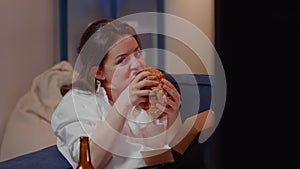 Business woman watching TV eating burger in living room
