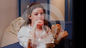 Business woman watching TV eating burger in living room