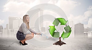 Business woman watering green recycle sign tree on city background