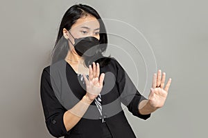 Business woman wearing black mask with both hands stopped