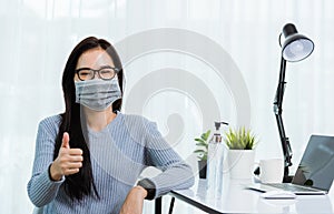 Business woman wearing face mask protective working from home office show finger thumber for good job sign