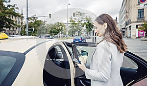 business woman wearing a suit entering taxi