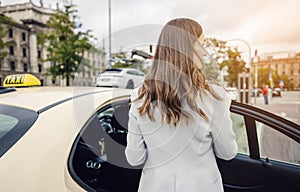 business woman wearing a suit entering taxi