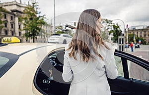 business woman wearing a suit entering taxi