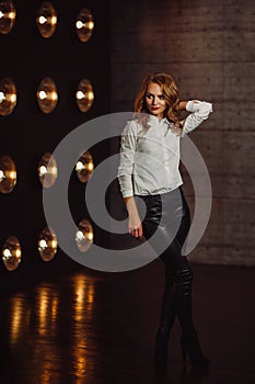 Business Woman in a white shirt against the background of burning lamps in the interior of a dark Studio.Model with long hair and