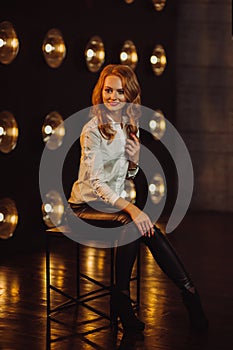 Business Woman in a white shirt against the background of burning lamps in the interior of a dark Studio.Model with long hair and