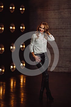 Business Woman in a white shirt against the background of burning lamps in the interior of a dark Studio.Model with long hair and