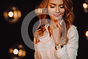 Business Woman in a white shirt against the background of burning lamps in the interior of a dark Studio.Model with long hair and