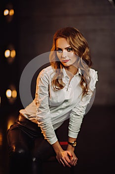 Business Woman in a white shirt against the background of burning lamps in the interior of a dark Studio.Model with long hair and