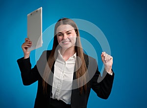 Business woman in white shirt and black suit standing and holding clipboard by her right hand and looking forward, rejoicing in