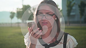 Business woman in white shirt and glasses speaks by phone, the girl is indifferent and daunting to the interlocutor.