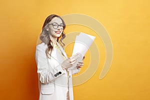 business woman in white suit holding documents on orange isolated background, girl manager in glasses with papers