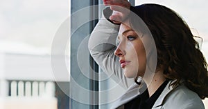 Business woman at window, thinking about crisis and depression with stress, financial trouble with mental health. Debt