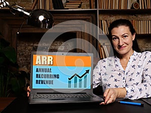 Business woman at work with financial reports  ARR ANNUAL RECURRING REVENUE and a laptop photo