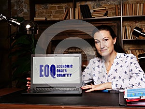 Business woman at work with financial reports  EOQ ECONOMIC ORDER QUANTITY and a laptop