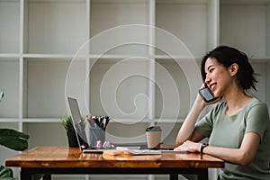 Business woman working for accounting financial and taking notes in notebook during call for consultation at home