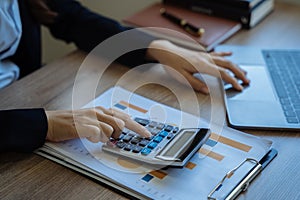 business woman working on calculator to calculate financial data report, accountancy document and laptop computer at office,