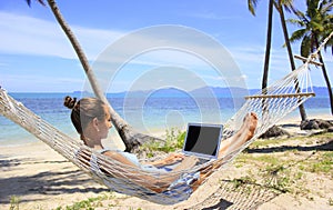 Business woman working in a hammock on the beach