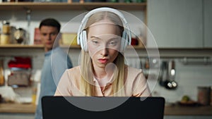 Business woman working home on laptop with headset man trying distract closeup