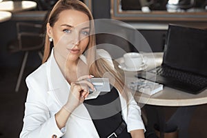 Business woman working with laptop in cafe, holging credit card