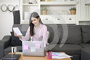 Business woman is working with laptop computer and analyzing business growth graph data in living room, Work from home ,