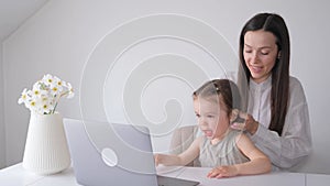 Business woman working on laptop at home with child. The child interferes with the mother's work
