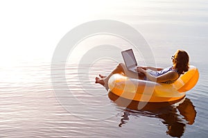 Business woman working on a laptop in an inflatable ring in the