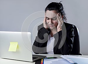 Business woman working on laptop at office in stress suffering intense headache migraine