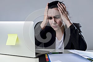 Business woman working on laptop at office in stress suffering intense headache migraine