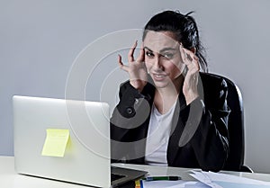 Business woman working on laptop at office in stress suffering intense headache migraine